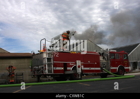 Fire ladder truck spraying wter on a fire in a greenhouse at a nursery in Menomonee Falls Wisconsin Stock Photo