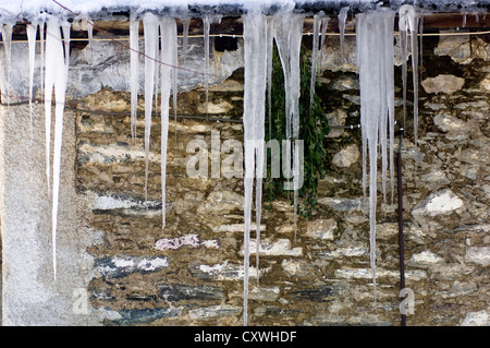 Melting icicles hanging from a house´s roof Stock Photo