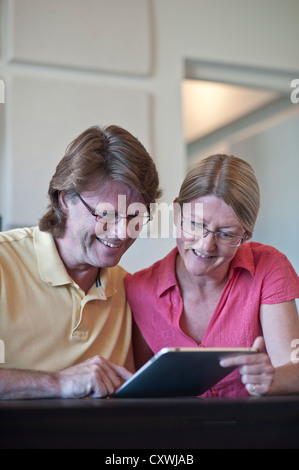 Attractive couple at home using their tablet computer together in light contemporary living room Stock Photo