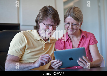 Attractive couple at home using their iPad tablet computer together in light contemporary living room Stock Photo