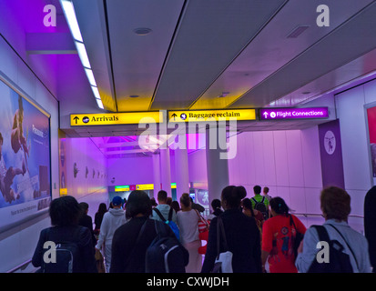 ARRIVALS Airline passengers arriving at Heathrow airport walkway lit by calming suffused colours heading for arrivals and baggage reclaim areas Stock Photo