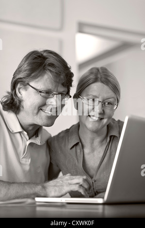 40years age  couple at home using their laptop computer together, in light contemporary living room office (B&W conversion) also in colour Stock Photo