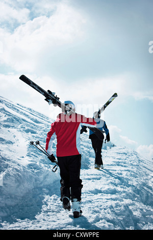 Skiers climbing up snowy mountainside Stock Photo