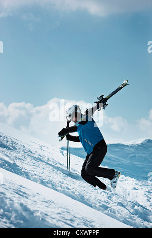Skier climbing up snowy mountainside Stock Photo