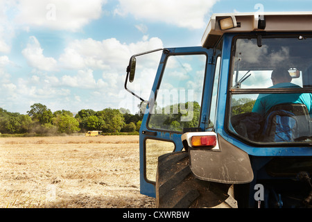 Farmer sitting in tractor in crop field Stock Photo