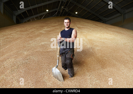Farmer standing in shed of grain Stock Photo