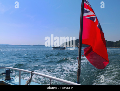 Flag waving from boat on water Stock Photo