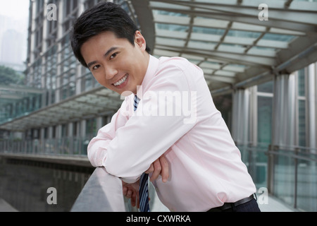 Smiling businessman leaning on banister Stock Photo