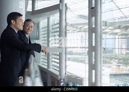 Businessmen leaning on banister Stock Photo