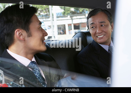 Businessmen riding together in taxi Stock Photo