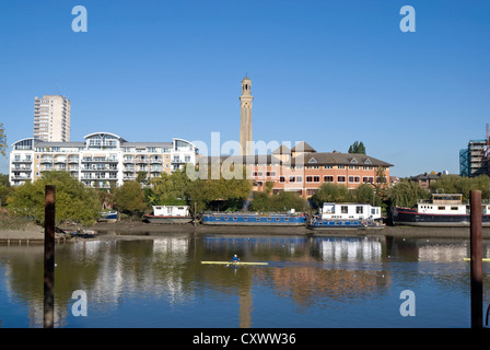 view from kew across the river thames towards luxury apartment blocks of brentford, with male canoeist in mid-river Stock Photo