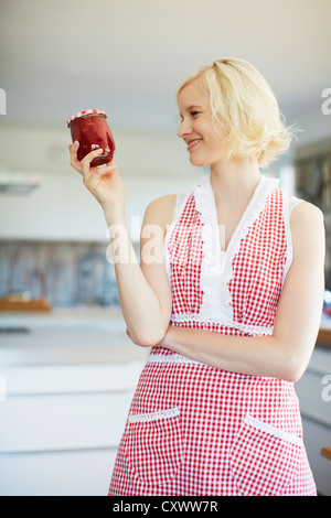 Woman holding jar of jelly in kitchen Stock Photo