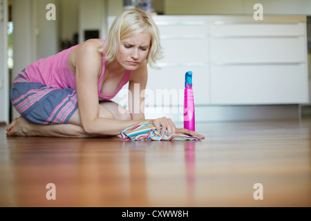 Frowning woman polishing wooden floor Stock Photo