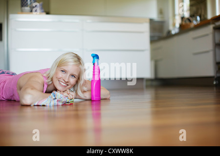 Smiling woman polishing wooden floor Stock Photo