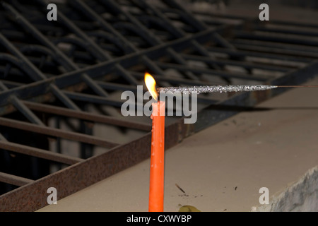 Lighting a sparkler with an orange candle. These sparklers are lit by exposing them to the flame of a candle for some time. Stock Photo