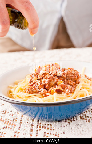 Serving of pasta bolognaise. The chef is adding olive oil on top. Stock Photo
