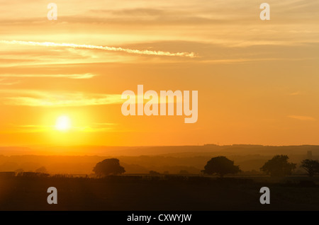 Setting sun seen to disappear behind horizon looking towards Durham the Cathedral tower just made out in the distance mist Stock Photo