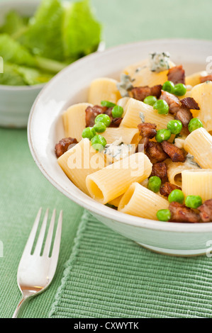 Closeup of a bowl of white pasta served with peas, bacon and blue cheese Stock Photo