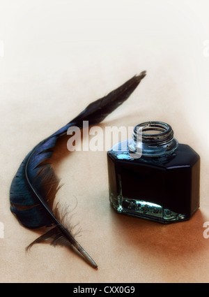 Feather and ink bottle on brown paper background Stock Photo