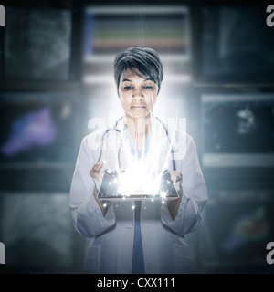 Mixed race scientist holding glowing digital tablet Stock Photo