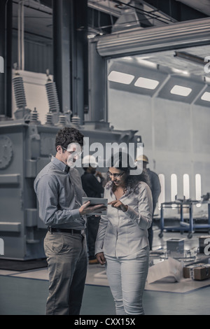 Workers using digital tablet together in factory Stock Photo