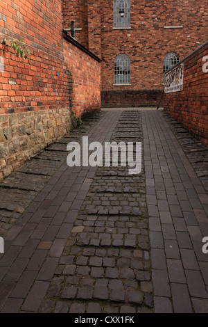 Cobbled street in an urban street with brick walls Stock Photo