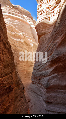 A narrow passage through a rock walls carved by time and illuminated by light Stock Photo