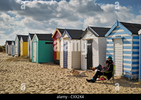 Relaxing outside beach huts in Southwold Stock Photo