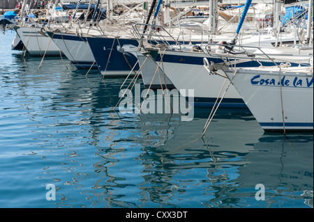 Yacht moored in the harbour at Puerto Mogan Gran Canaria Canary Islands Spain. In attractive line with reflections in the water Stock Photo