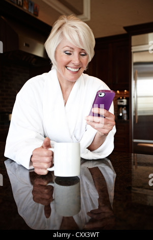 Caucasian woman in robe using cell phone Stock Photo