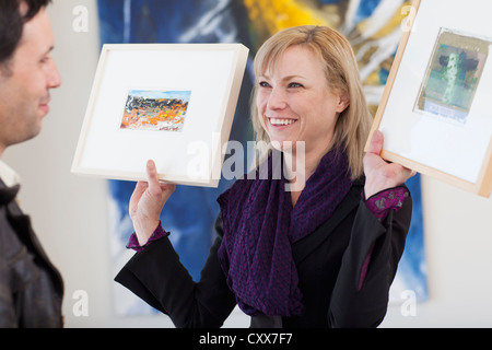 Caucasian woman showing paintings to customer Stock Photo