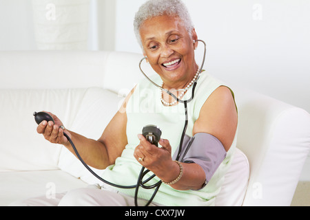 African American woman taking her blood pressure Stock Photo