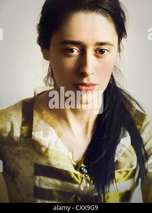 Portrait of a young woman with a sad expression, long dark hair & brown eyes, dressed in a green historical gown. Stock Photo