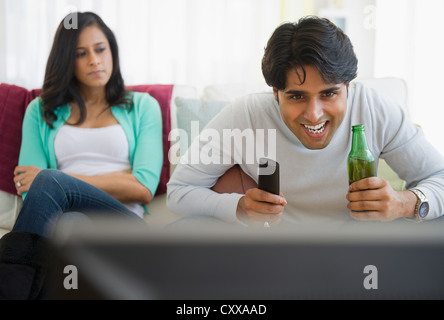 Angry girlfriend watching husband enjoy television Stock Photo