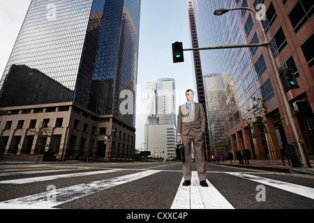 Businessman standing in urban crosswalk Stock Photo