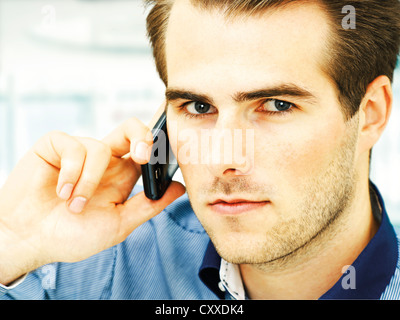 Young man speaking on his mobile phone, serious face Stock Photo