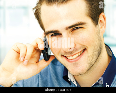 Smiling young man speaking on his mobile phone Stock Photo