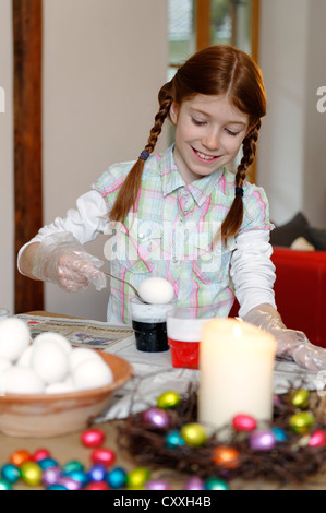 Kids dyeing Easter eggs. Children in bunny ears dye colorful egg for