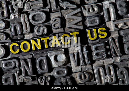 Old lead letters forming the words 'CONTACT US' Stock Photo