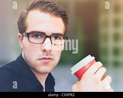 Young businessman wearing glasses, holding a cup of coffee Stock Photo