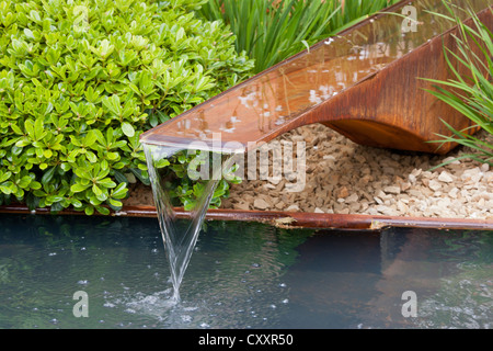 a garden with garden rill water feature made from copper water marginal plants planting small pond UK Stock Photo