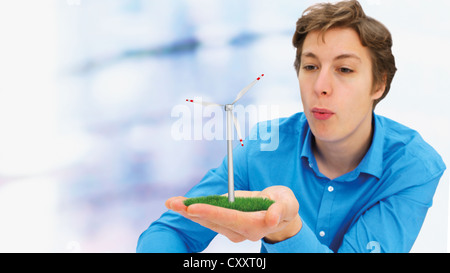 Young Man blowing onto a wind turbine Stock Photo