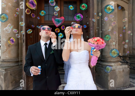 Bride and groom, bridal couple blowing bubbles, in front of St. Mary's Church, Krakow, Poland, Europe Stock Photo