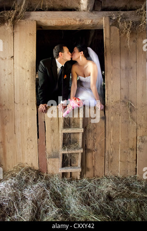 Bride and groom, bridal couple kissing in a barn, hay shed Stock Photo