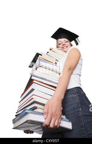 University graduate wearing a graduation cap and carrying a pile of books Stock Photo