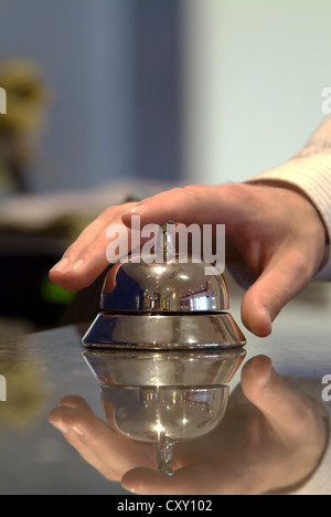 Hand resting on a hotel reception bell Stock Photo