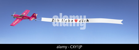 Plane in the sky pulling a banner with the message Ich liebe dich, German for I love you, illustration Stock Photo