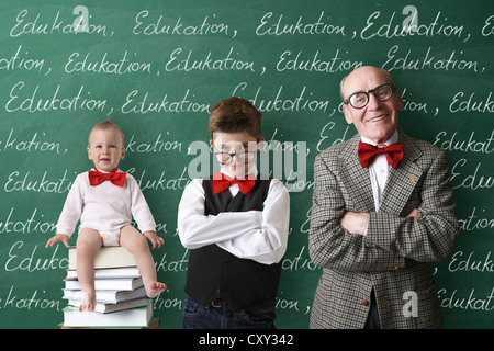 Infant, schoolboy and a professor standing in front of the school blackboard with the word Education written repeatedly Stock Photo