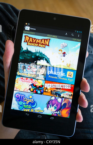Man holding Google Nexus 7 tablet computer running android showing games for sale at Google Play store Stock Photo