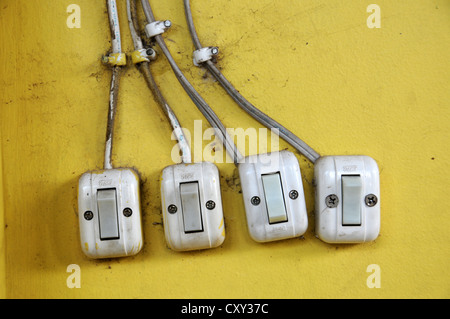 Four light switches on a yellow wall, Sihanoukeville, Cambodia, Asia Stock Photo